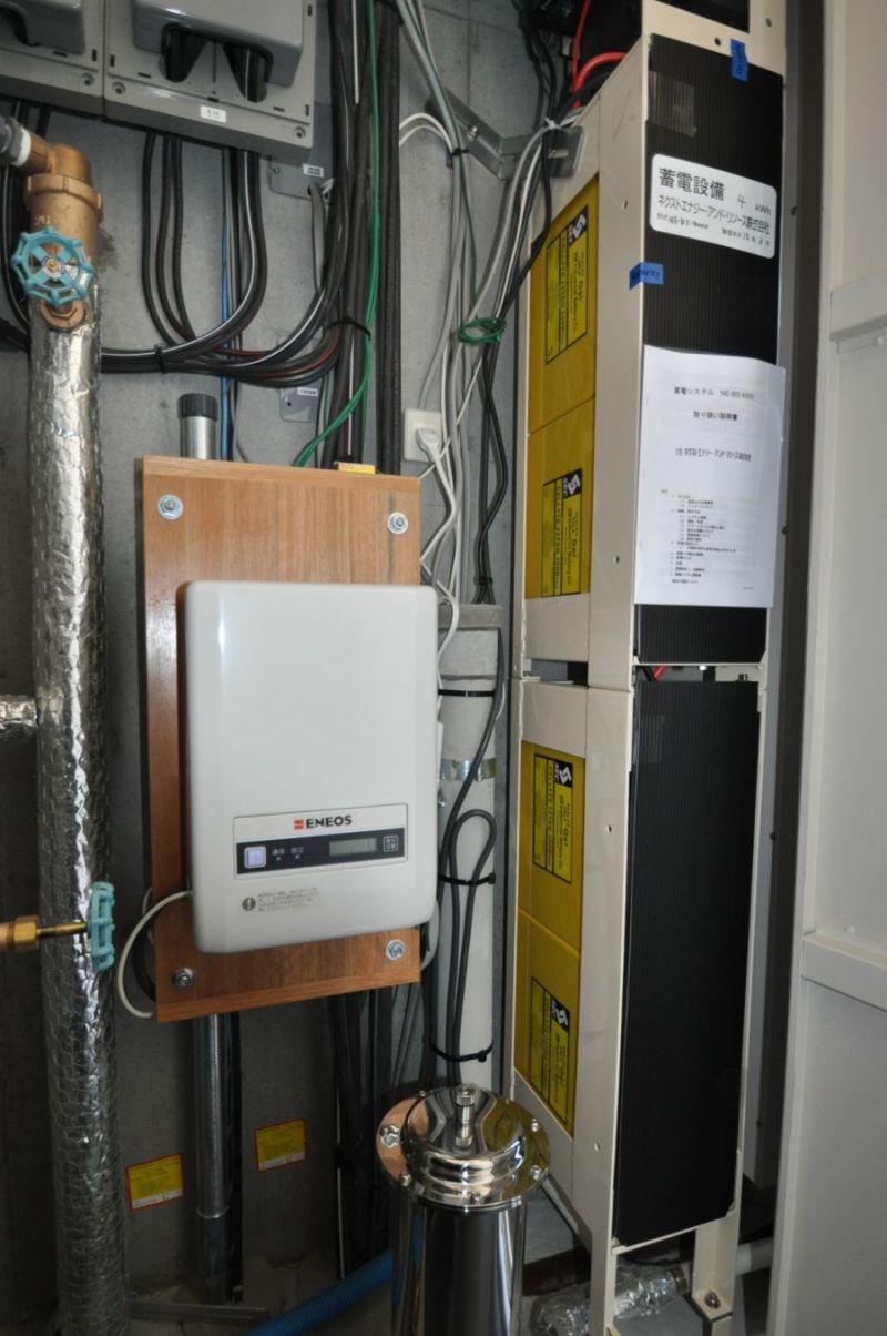 太陽光発電からの直流電力を家庭で使える交流に交換するパワーコンディショナ(中央の四角い箱)。右側が蓄電池。いずれも各住戸のパイプスペース内に設けた